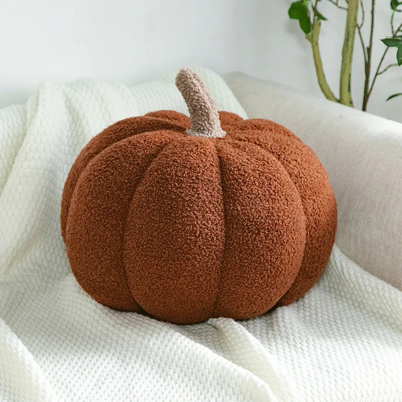 A round, fuzzy brown pumpkin plush decoration resting on a white textured fabric.