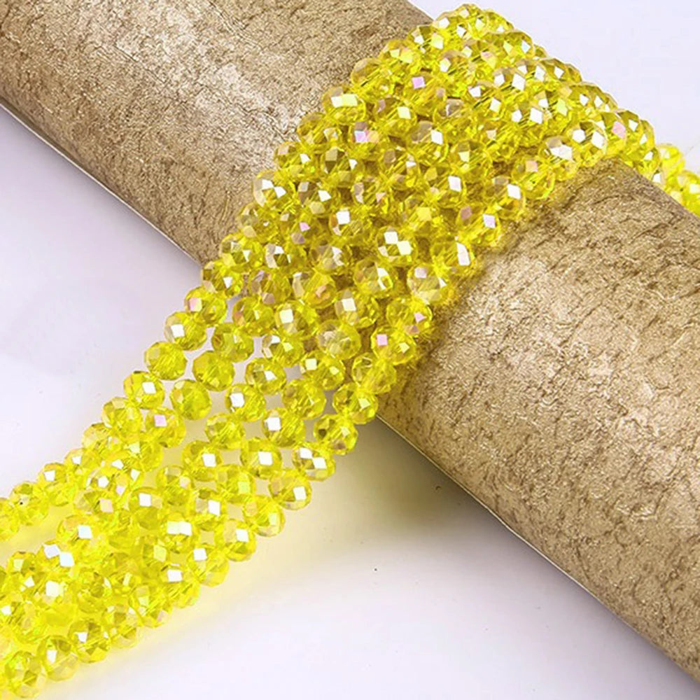 A strand of bright yellow faceted rondelle glass beads is draped over a cylindrical object.