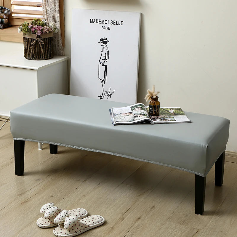 A gray waterproof stretch dining bench cover is displayed on a wooden bench in a bright room.
