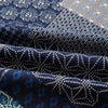 Close-up of dark blue and white patterned linen fabric folds showing intricate geometric designs