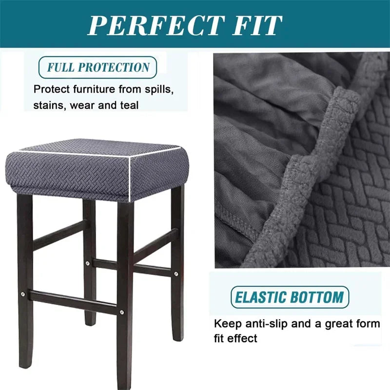 A dark gray jacquard elastic bar stool slipcover with a textured fabric and a padded seat.