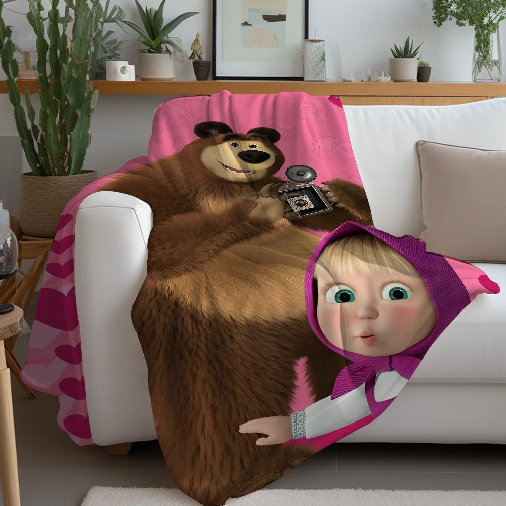 A cartoon bear character wearing a pink blanket is featured on a white fleece blanket.