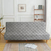A gray velvet non-slip armless sofa cover displayed on a wooden floor with a patterned rug.