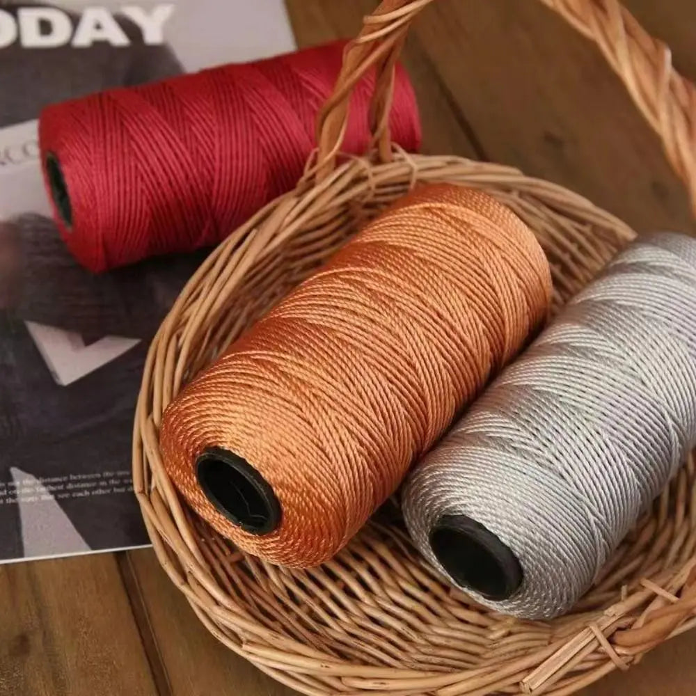 A basket filled with spools of red and copper-colored cotton silk thread for knitting and crafting.