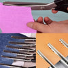 A close-up of stainless steel zig zag tailor sewing scissors being used to cut pink fabric.