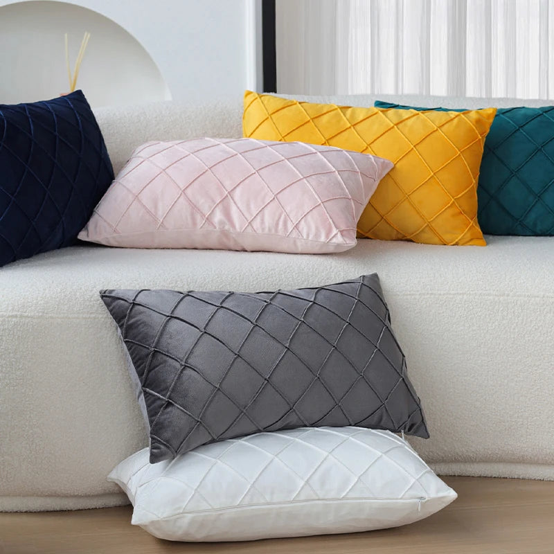 A set of two ultra-soft velvet decorative pillow covers in shades of navy, pink, yellow, and gray displayed on a sofa.