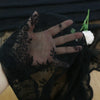 Black floral lace sheer fabric with a mesh hand, displayed against a dark background.