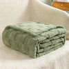 A stack of olive green checkered fleece throw blankets resting on a cream-colored textured surface.