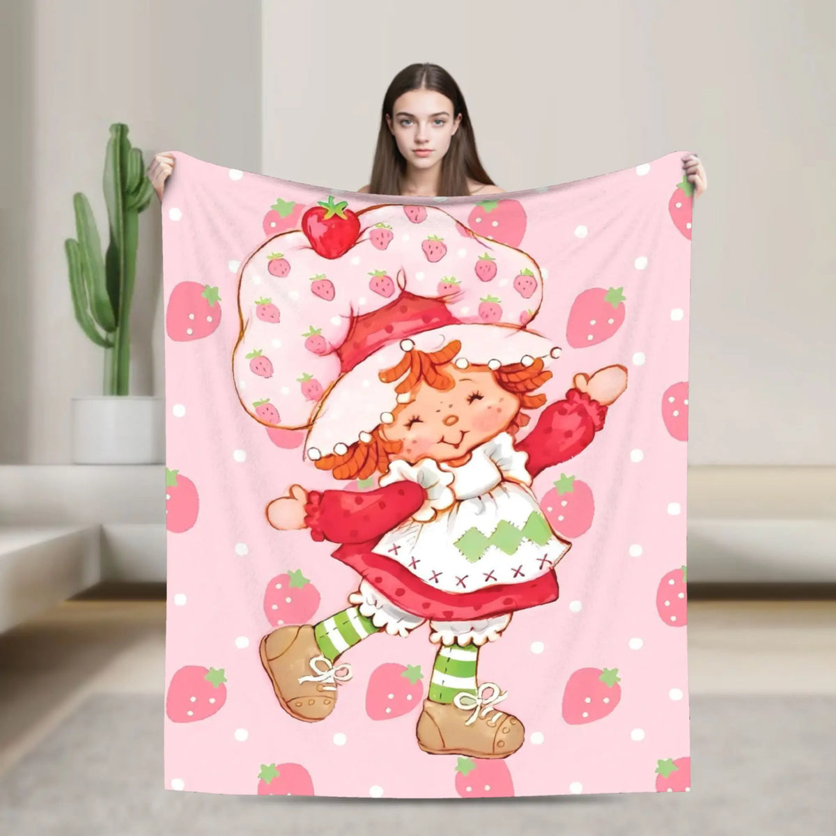 A pink strawberry shortcake plush throw blanket featuring a cute character with red hair and strawberries.