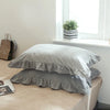 A set of two soft plaid washed cotton pillowcases with ruffled edges resting on a light-colored table.