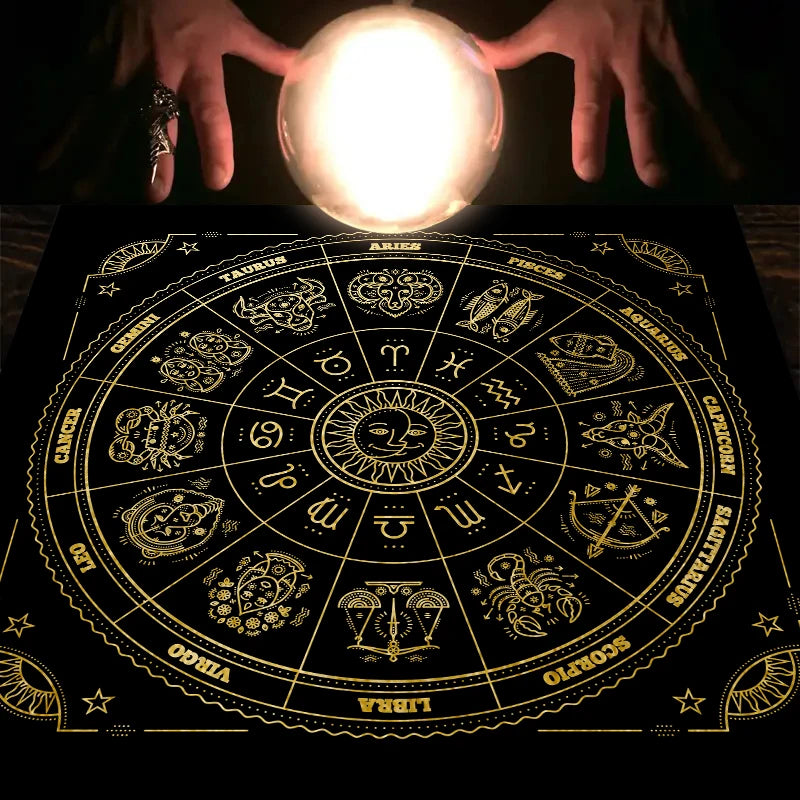 Hands holding a bright light source above a detailed astrological chart on a black cloth.