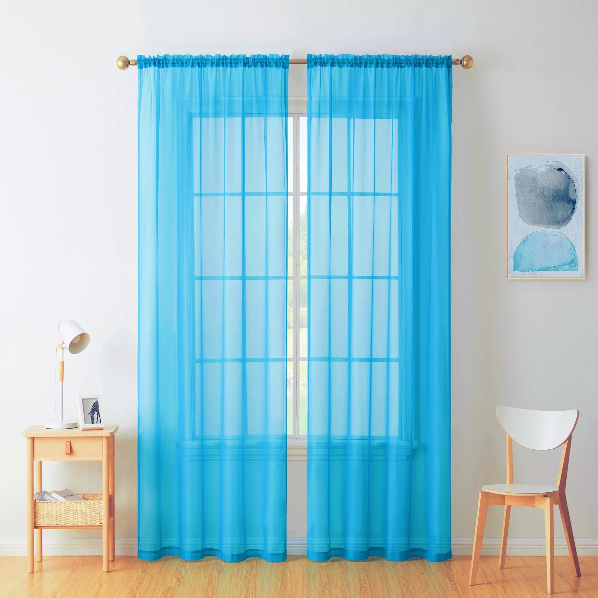 A pair of light blue sheer voile curtains hanging in a window frame against a white wall.