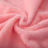 Close-up of soft pink coral velvet cleaning face towels rolled into a swirl.