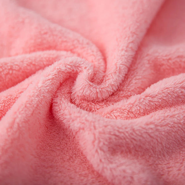 Close-up of soft pink coral velvet cleaning face towels rolled into a swirl.