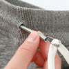 A hand is using a metal drawstring threader tool to open the neck of a gray hoodie.