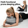 A woman is using a multi-functional prone sleeping pillow while lying down and looking at her phone.