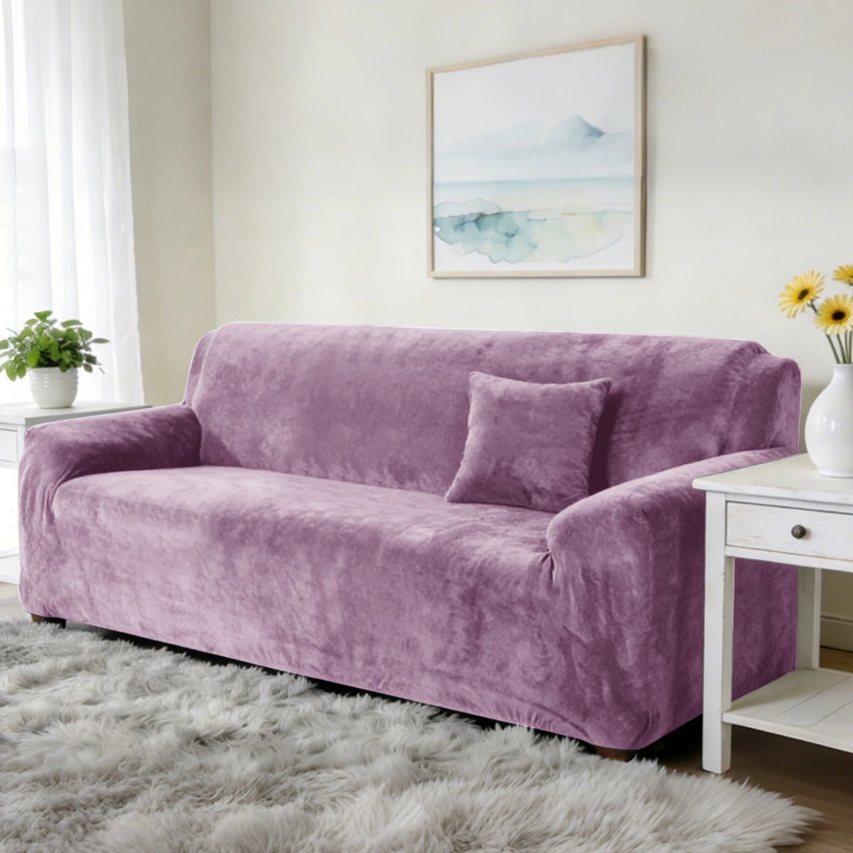 A mauve stretch velvet sofa slipcover with a throw pillow on a light rug and framed artwork.