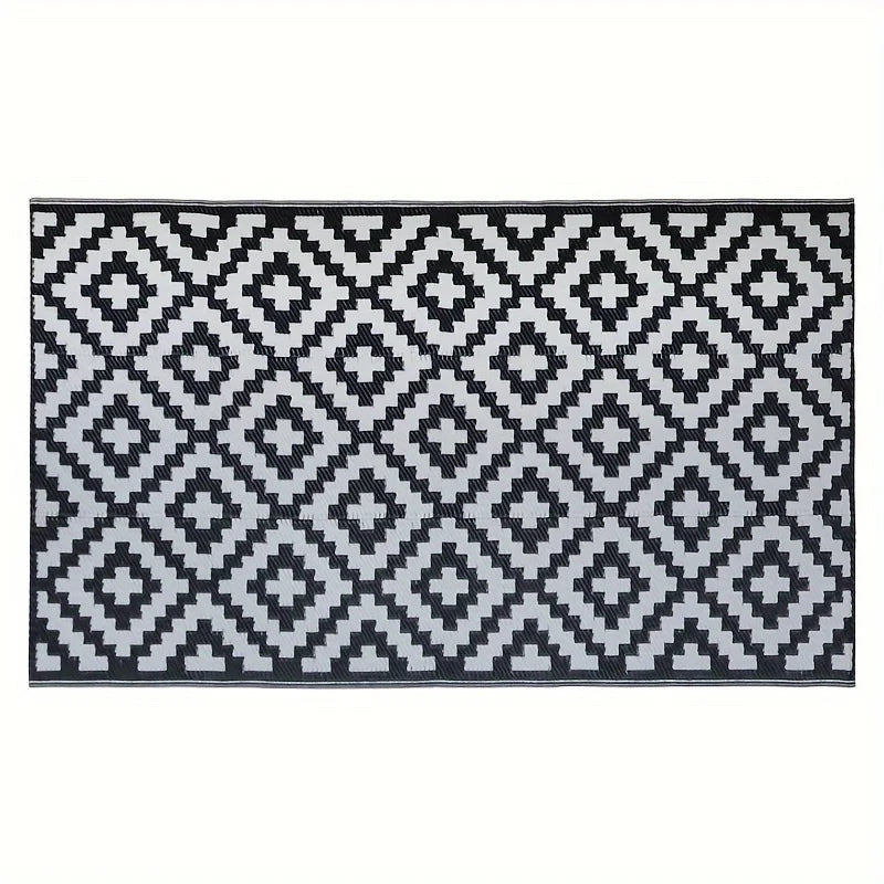 A black and white geometric patterned outdoor rug with a diamond lattice design.