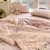Pink cartoon quilting comforter with small animal patterns displayed on a bed.