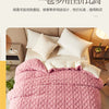 A pink quilted fleece blanket is displayed on a bed with white pillows and bedding.