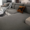 A modern gray sofa covered with a textured fleece fabric and decorated with an orange throw pillow.