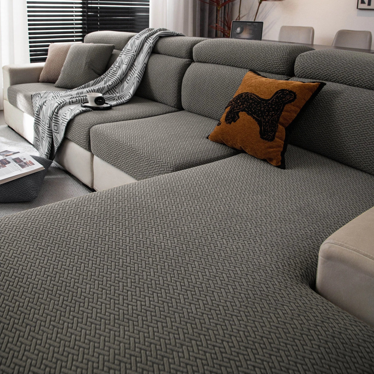 A modern gray sofa covered with a textured fleece fabric and decorated with an orange throw pillow.