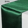 A dark emerald green satin table runner draped elegantly.