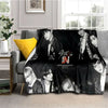 A black fleece throw blanket featuring multiple portraits of Stray Kids members.