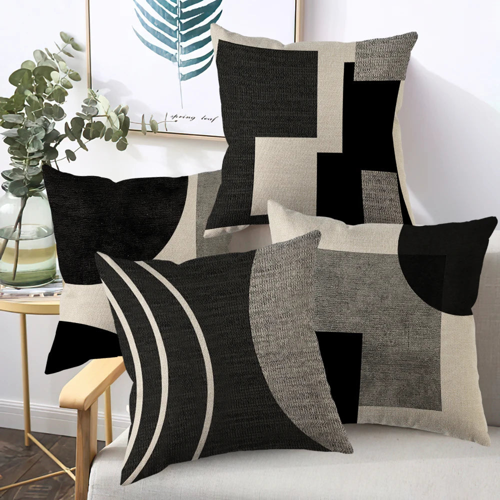 A set of abstract geometric throw pillow covers in black, white, and beige tones displayed on a sofa.