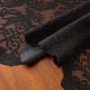 Elegant black lace tablecloth with floral embroidery draped over a wooden surface.
