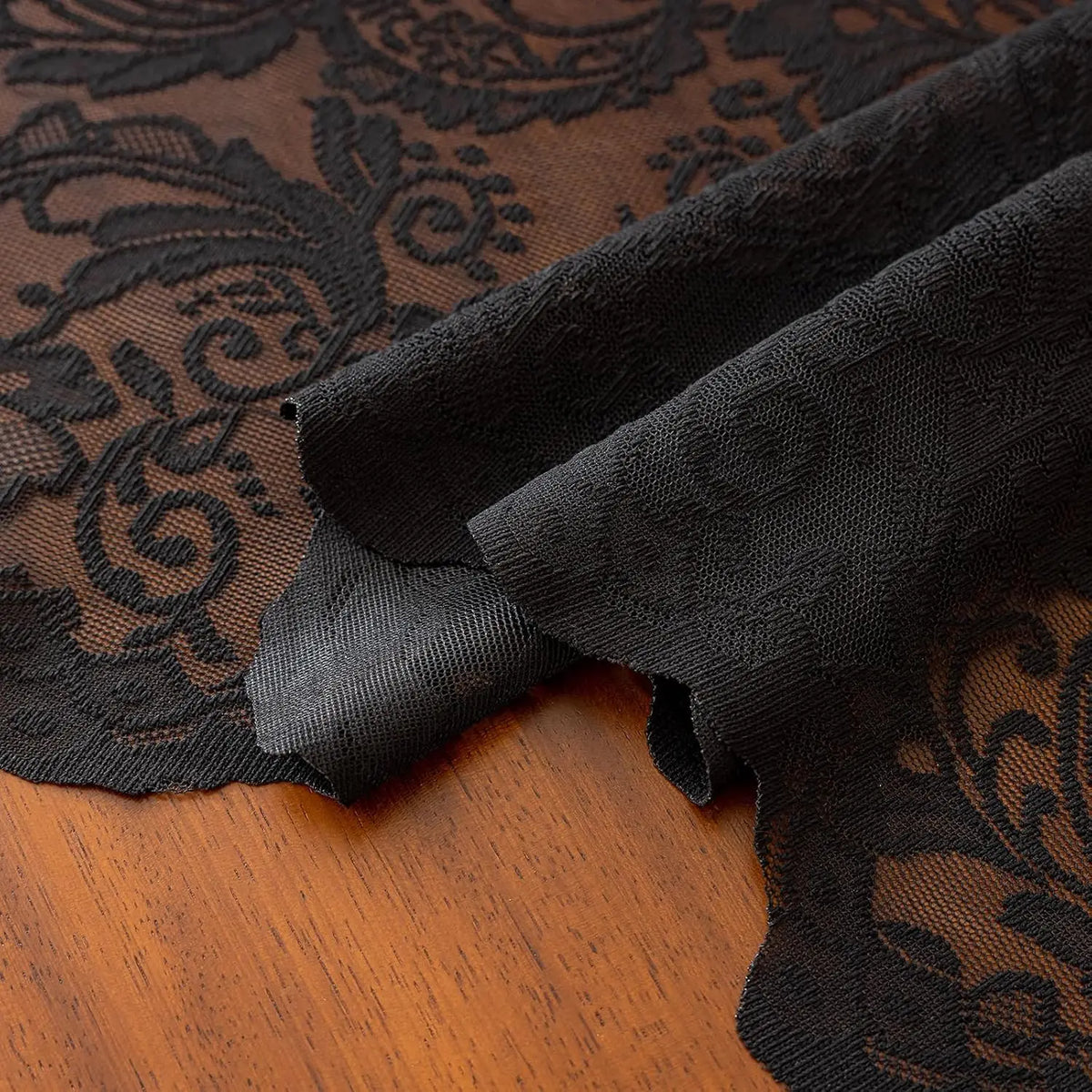 Elegant black lace tablecloth with floral embroidery draped over a wooden surface.