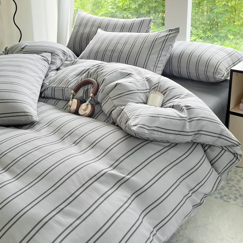 A gray and white striped duvet cover set with matching pillows on a bed.