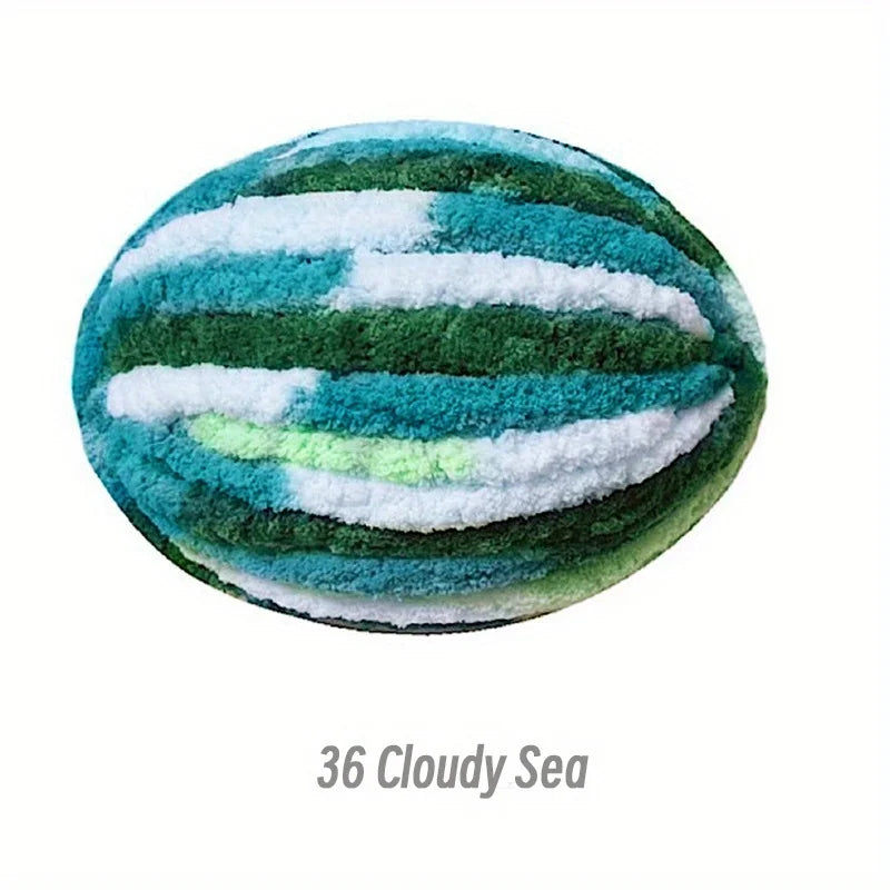 A round, fuzzy sea-themed ball knitted with green and blue yarn stripes.