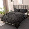 A black quilted duvet and pillow set displayed on a upholstered bed with a headboard.
