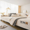 A white knitted plush sofa cover with brown and black animal designs displayed on a modern bed.