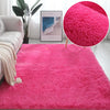 A vibrant pink plush area rug with a fluffy texture displayed in a bright room setting.