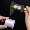 A hand holds a precision measuring tool used to measure the diameter of white nylon beading thread on a spool.