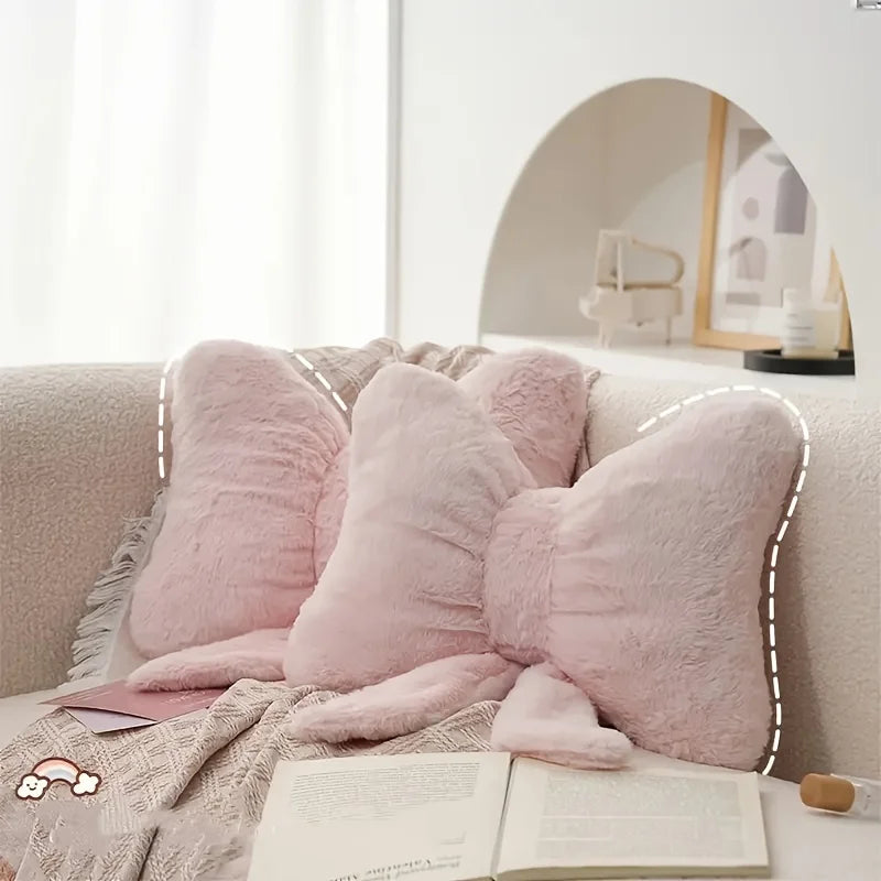 A grouping of soft pink faux fur decorative bow pillows on a light-colored sofa.
