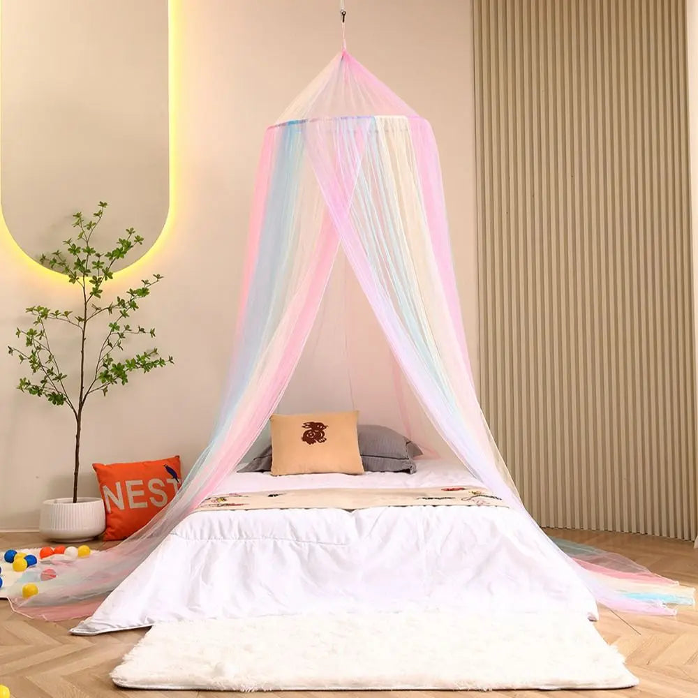 A bed decorated with a rainbow mesh mosquito netting canopy and pillows in pastel colors.