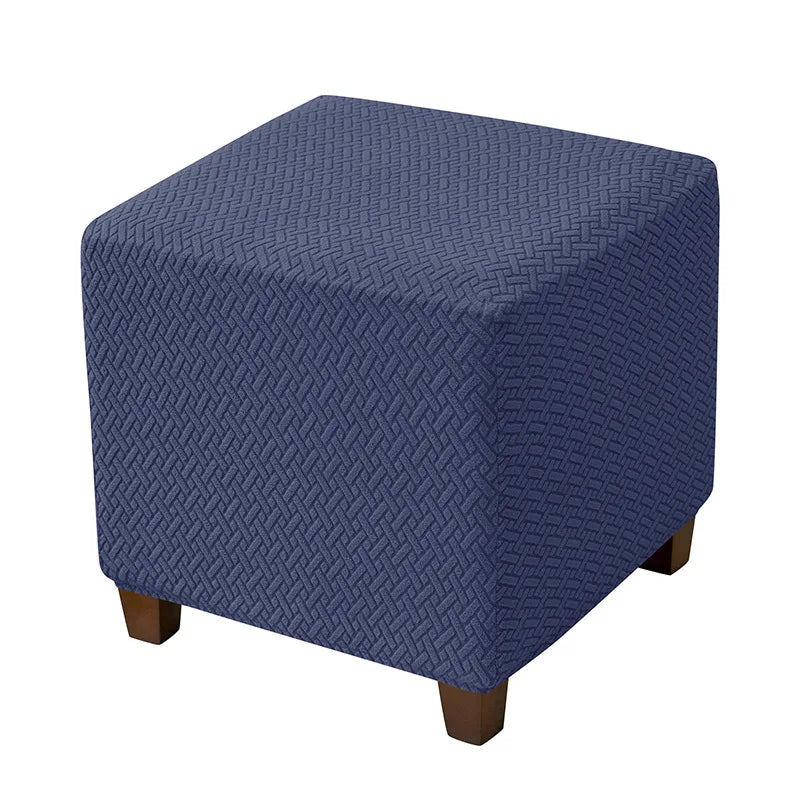 A dark blue jacquard stretch ottoman slipcover with a diamond pattern.