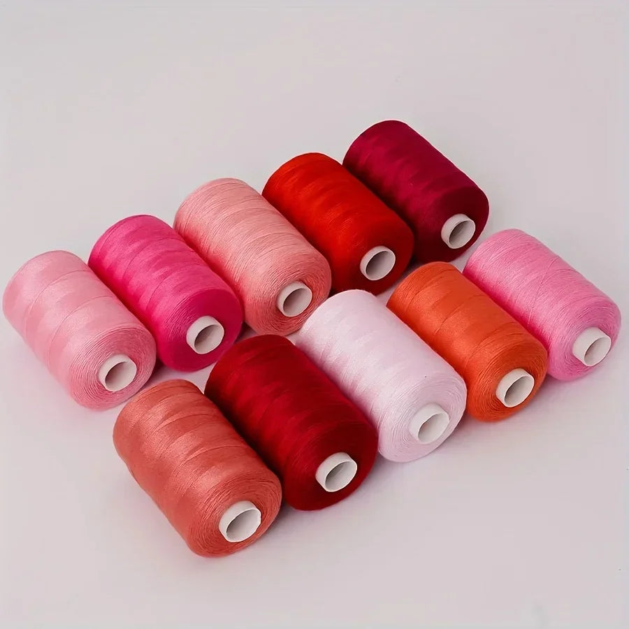 A collection of ten rolls of high-quality polyester sewing thread in various shades of pink, red, and orange.