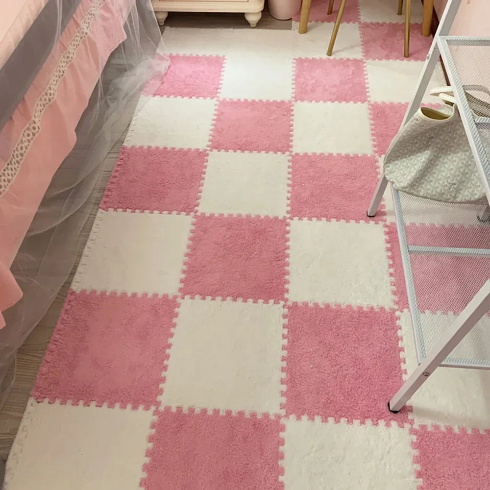 A pink and white checkered soft plush EVA foam play mat with square tiles on a light floor.