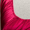 Close-up of a vibrant magenta satin bedding set with fitted sheets.