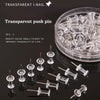 A collection of transparent push pins with steel tips displayed on a dark surface.