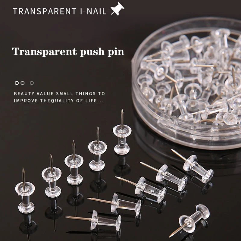 A collection of transparent push pins with steel tips displayed on a dark surface.