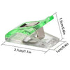 A clear plastic sewing clip with a green handle and silver clamp, shown from the side.