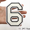 A hand holds a white and black letter patch shaped like the number six.