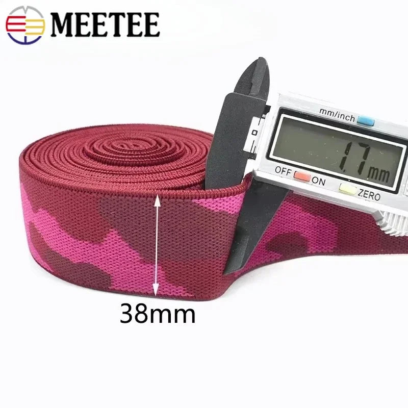 A roll of pink and dark red camouflage elastic stretch ribbon with a measuring tape attached.