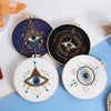 Three circular embroidery designs featuring stylized eyes and geometric star patterns on white fabric
