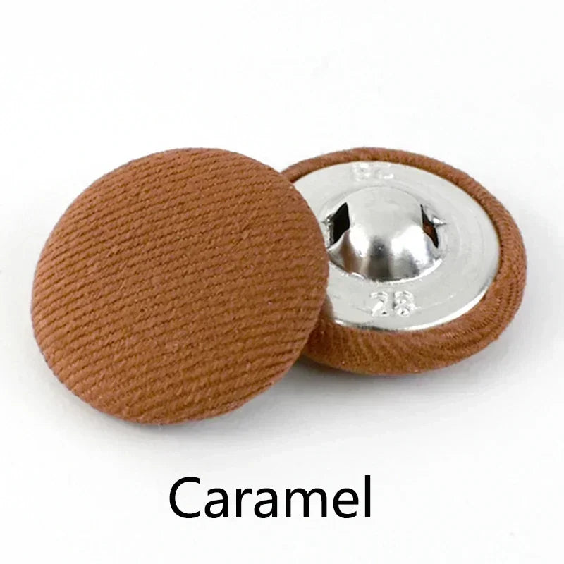 A round, brown fabric-covered shank button with a silver post is shown.